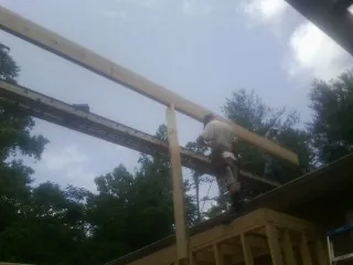 Carpenter setting a ridge beam over a new addition frame — Ice Dam Removal by Roofing Brothers in Bowie