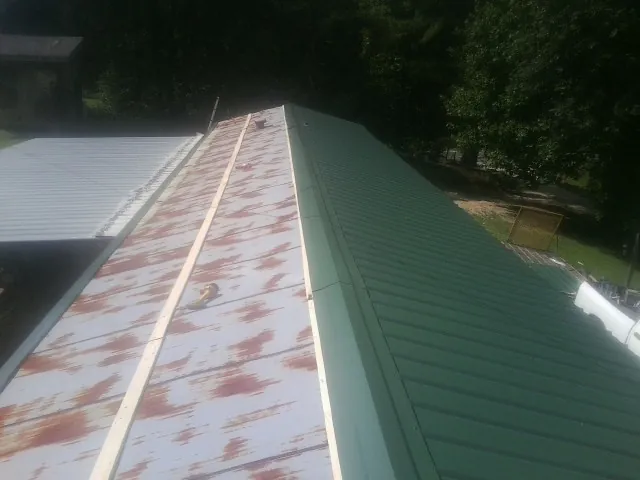 Old rusted panels beside newly installed green metal roofing — Wind Damage Roof Repair by Roofing Brothers in Bowie