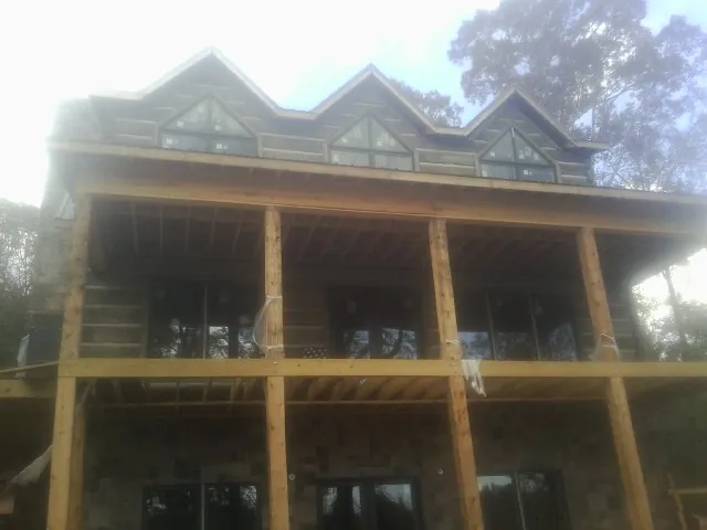 Dormers and porch framing on a large log home under construction — Roof Coating work by our crew in Bowie