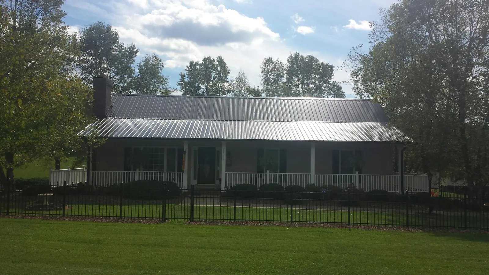Gray metal roof on a brick ranch with a full width front porch — Gutter Guard Installation work by our crew in Bowie