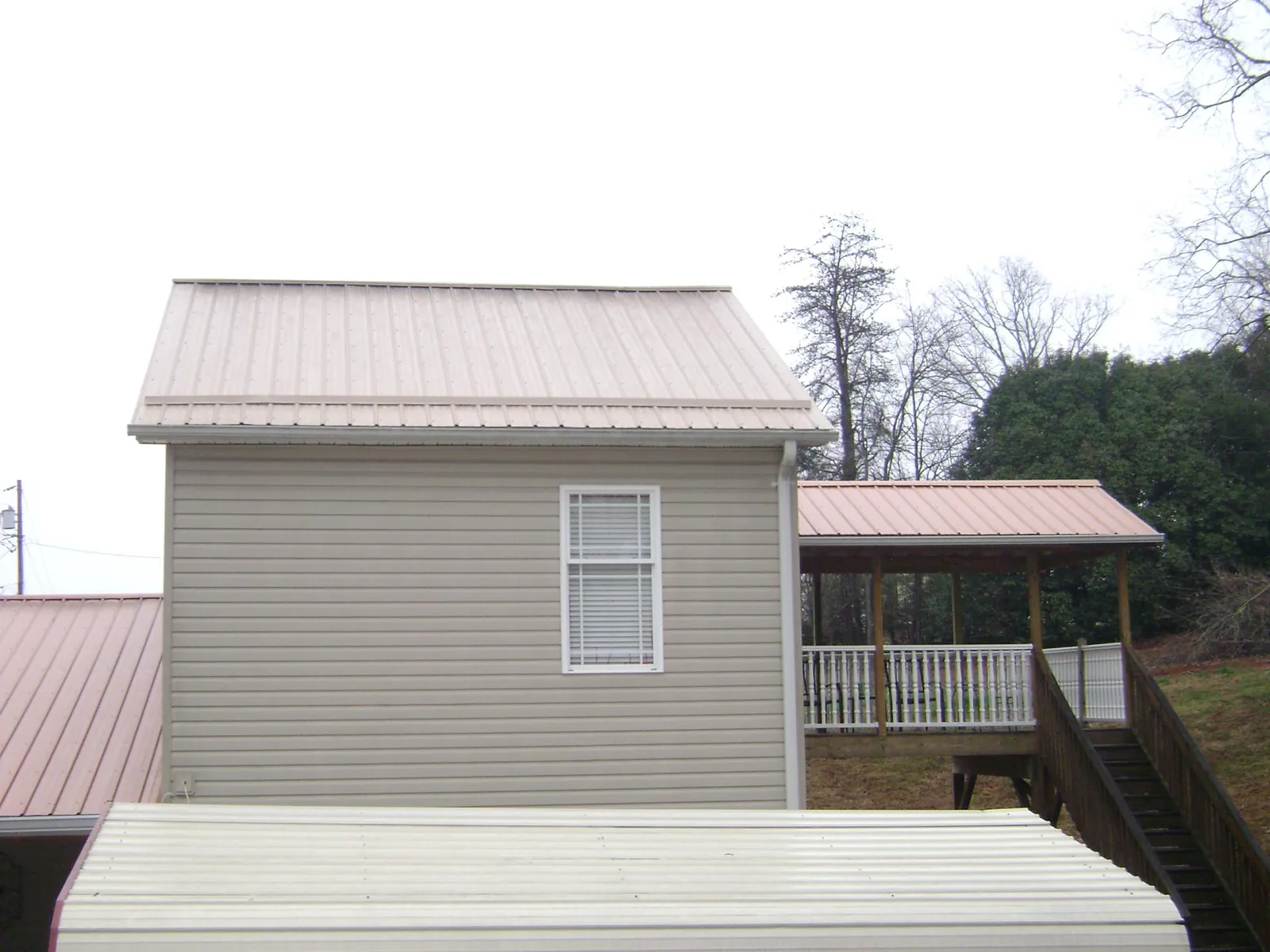 Tan metal roofs on a two story addition and attached porch, from a Roof Replacement job in Bowie